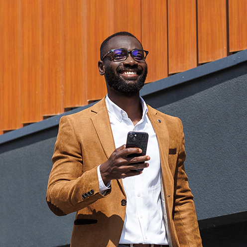Smiling man looking at his phone while walking.