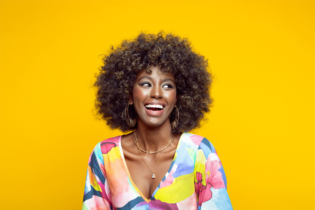 Smiling woman looking to the right, with a multi-colored blouse.